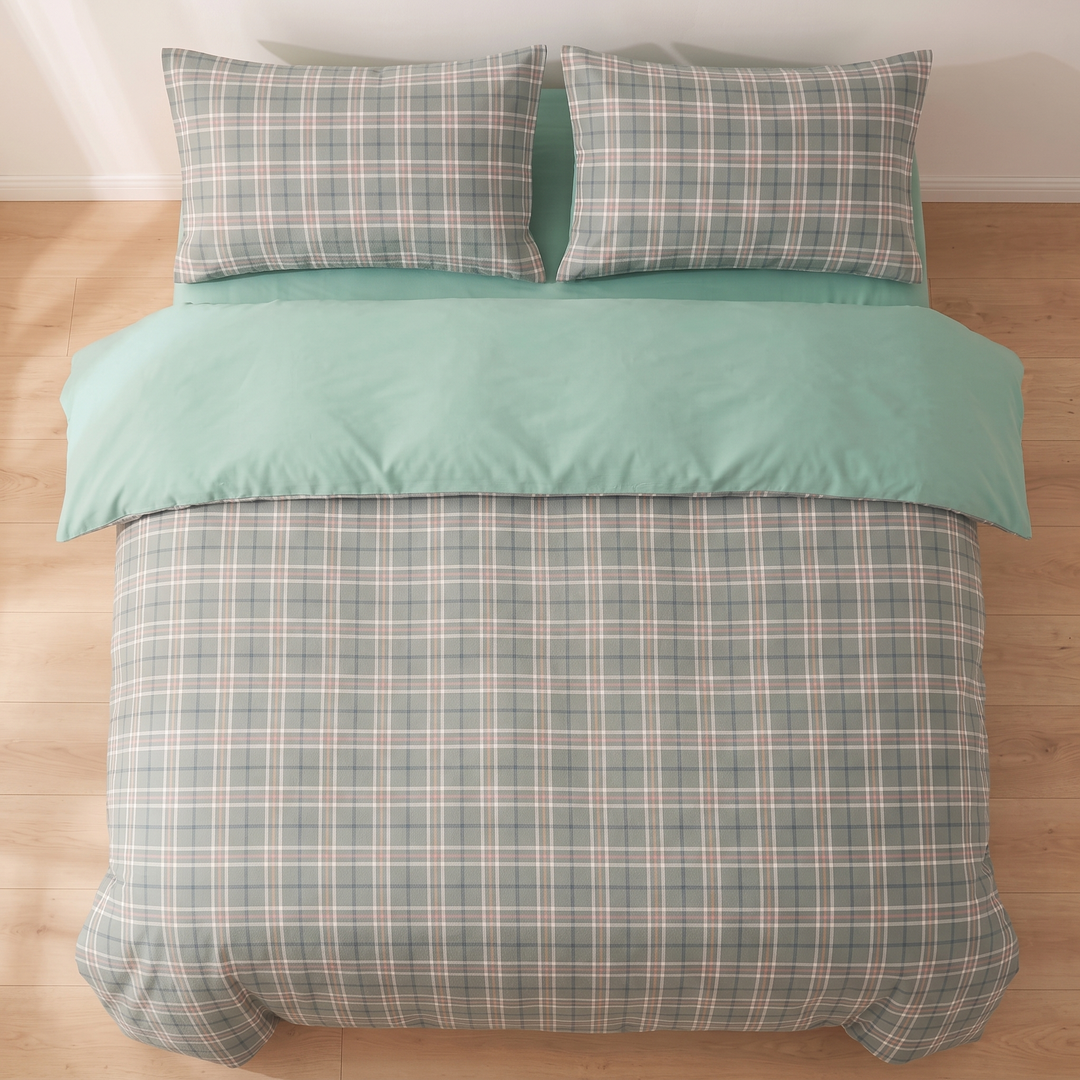 Cotton Duvet Cover Set in Sage Plaid – overhead view of made bed with two pillows on wood floor