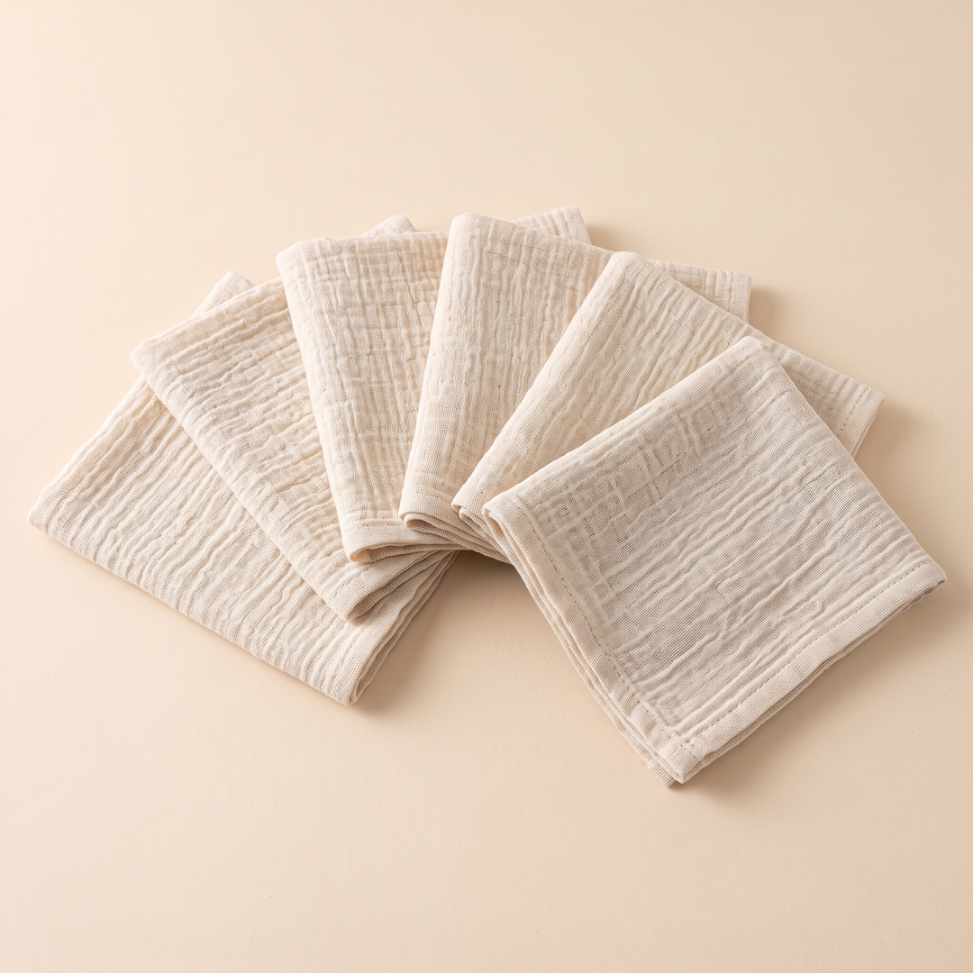 Cotton Gauze Napkins – Set of 6 in Oatmeal – spread like a hand of cards on a peach backdrop