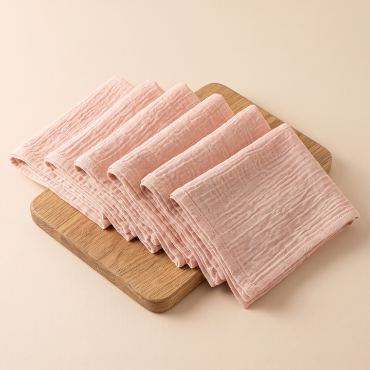 Cotton Gauze Napkins – Set of 6 in Peach – shingled across a wooden board with corners overhanging its edge