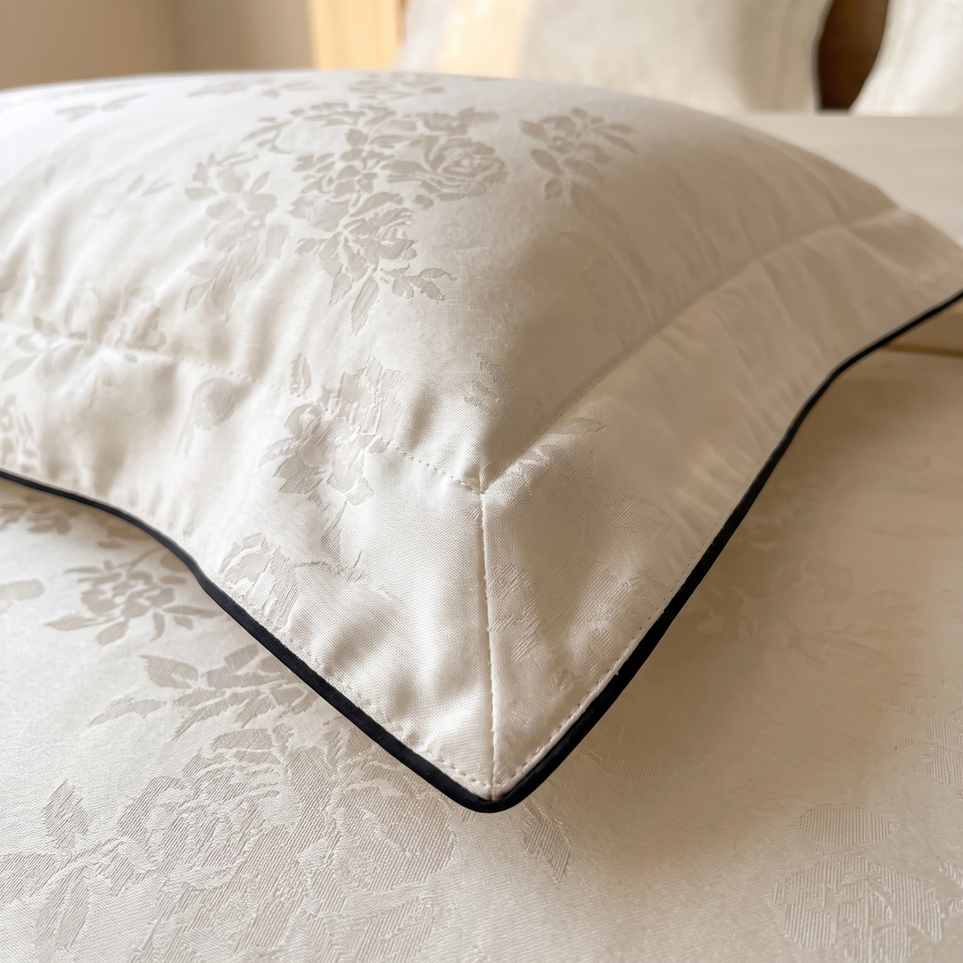 Cotton Jacquard Bedding Set in Cream Piped Floral – close-up of pillow sham corner with dark piping and floral jacquard weave