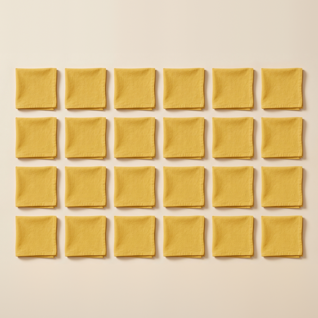 Cotton Cloth Napkins – Set of 24 in Golden Yellow – folded squares arranged in a grid, overhead view on cream background