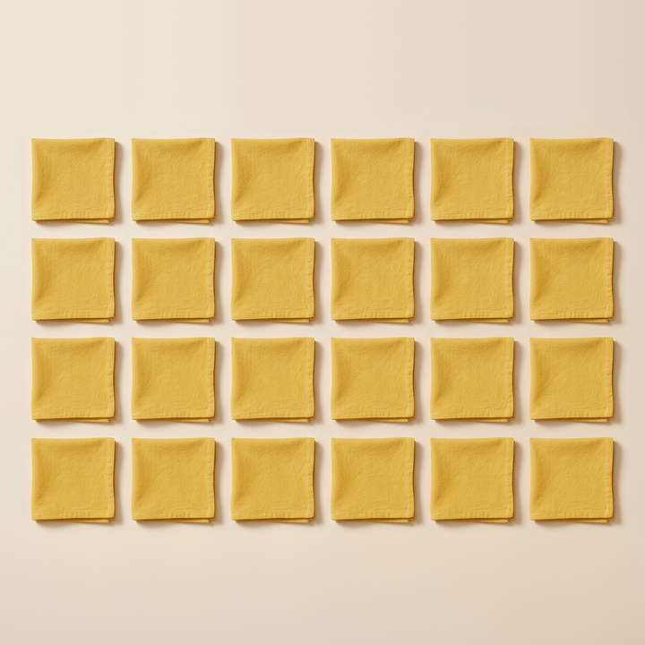 Cotton Cloth Napkins – Set of 24 in Golden Yellow – folded squares arranged in a grid, overhead view on cream background