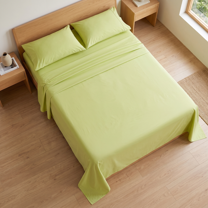 Cotton Flat Sheet Set – Percale, with 2 Pillowcases in Light Green – on a made bed with a wooden bench at its foot