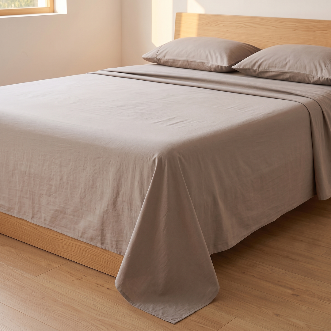 Cotton Flat Sheet Set – Percale, with 2 Pillowcases in Taupe – three-quarter view beside a sunlit window, wooden headboard