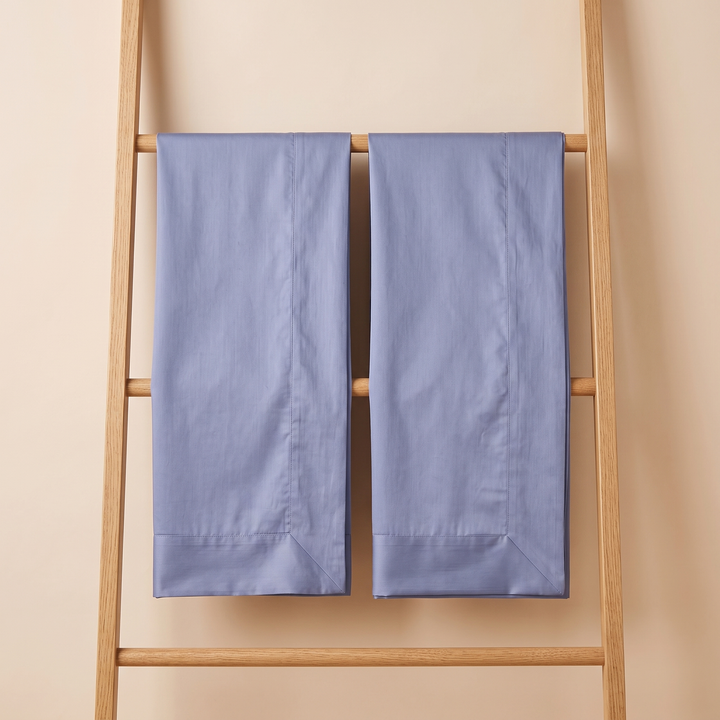 Cotton Sateen Pillowcases – Set of 2 in Dusty Blue – two pillowcases hung side by side over a wooden ladder