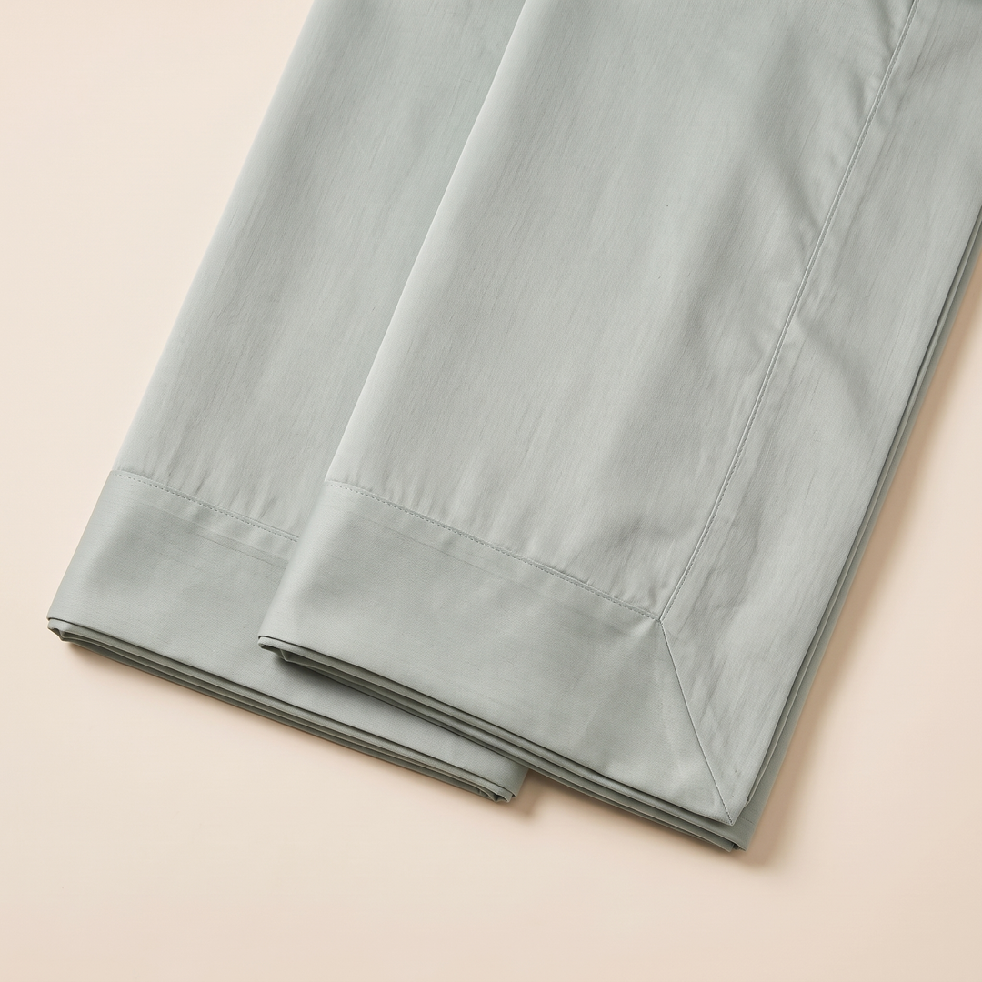 Cotton Sateen Pillowcases – Set of 2 in Sage – staggered folded corners laid flat on a plain backdrop