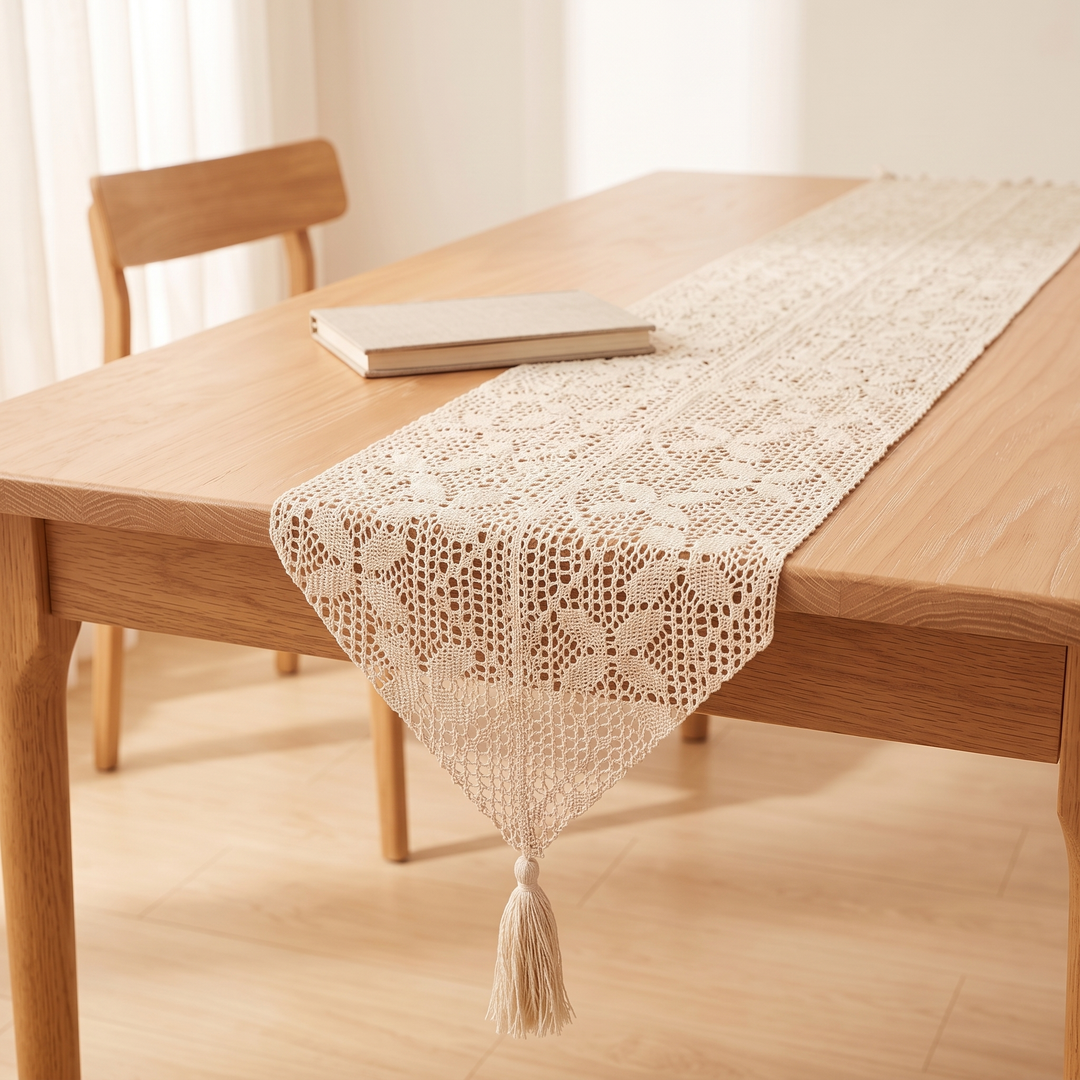 Crochet Table Runner in Ivory – Pointed Flower Grid – pointed end draped beside a closed book and wooden chair