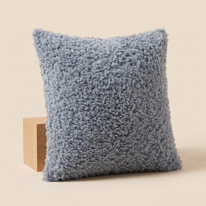 Curly Faux Fur Pillow Cover in Dusty Blue – tilted against a pale wood cube with soft shadow