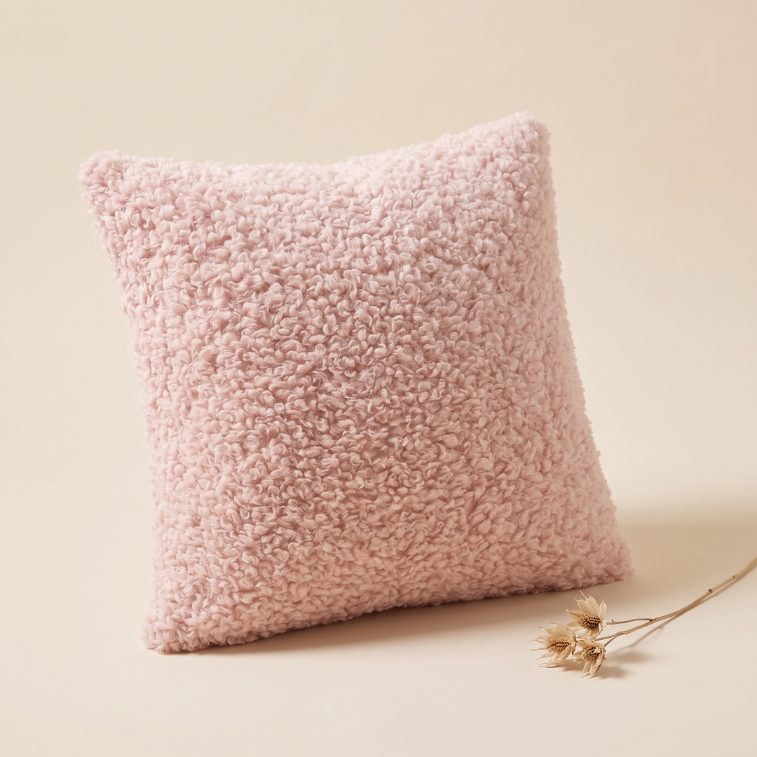 Curly Faux Fur Pillow Cover in Light Pink – propped with a dried flower stem lying beside it