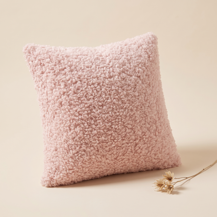 Curly Faux Fur Pillow Cover in Light Pink – propped with a dried flower stem lying beside it