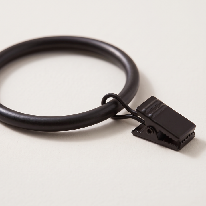 Metal Curtain Rings with Clips in Black – single ring with clip, angled close-up on off-white surface