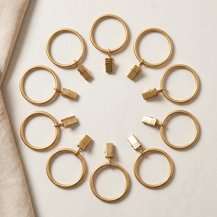 Metal Curtain Rings with Clips in Gold – ten rings with clips arranged in a circle beside linen fabric