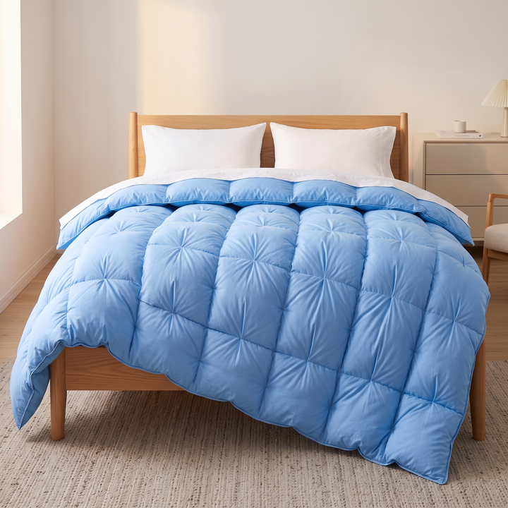Down Comforter – White Goose Down, Puffy Pinch-Pleat in Light Blue – straight-on view on wooden bed with nightstand and woven rug