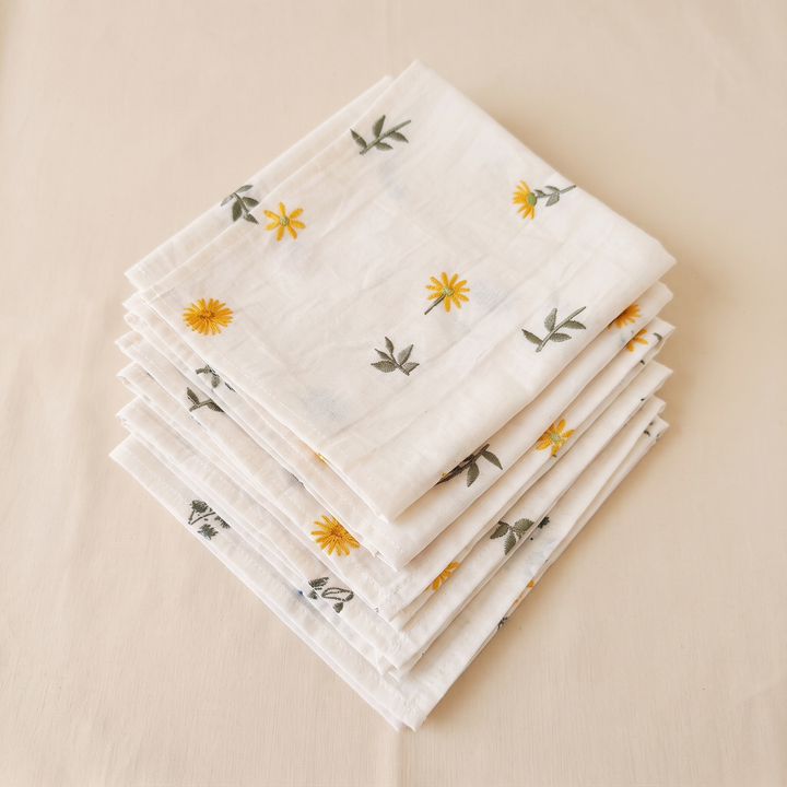 Embroidered Cotton Napkins – Set of 6 in Cream – Daisy – neatly stacked in a pile, seen from above on cream fabric