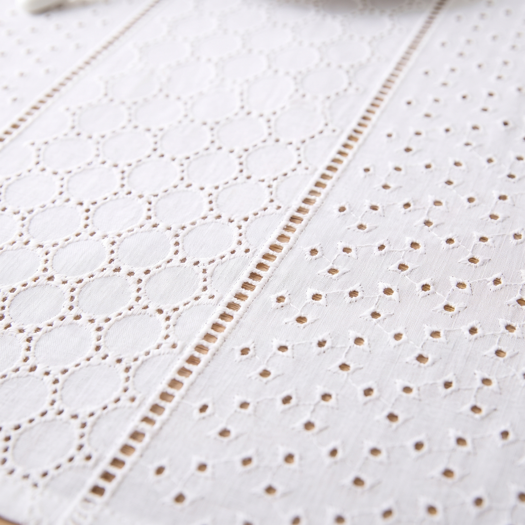 White Cotton Tablecloth – Embroidered in White – Eyelet Circles – close-up of eyelet circles and scattered cutwork on a wooden table