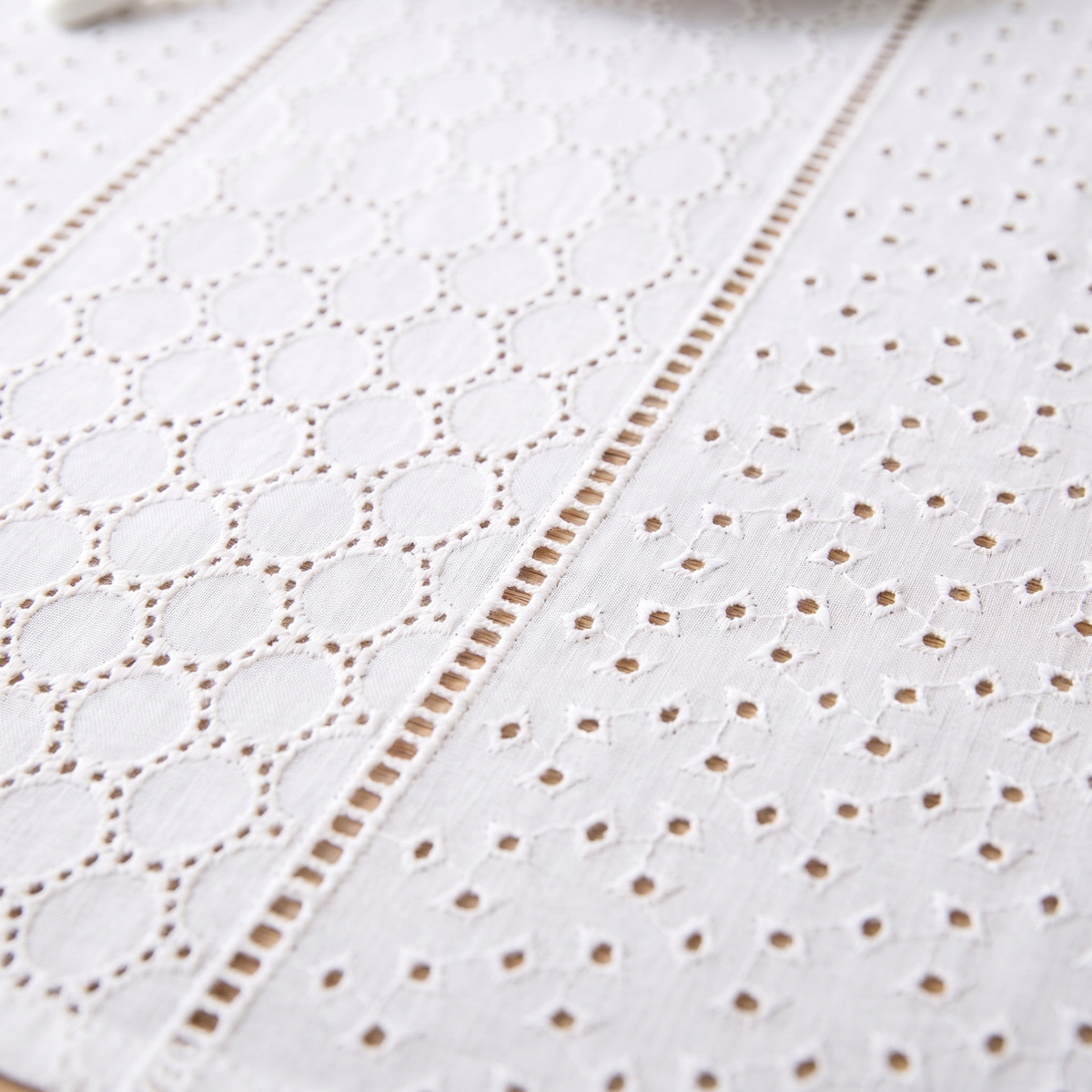 White Cotton Tablecloth – Embroidered in White – Eyelet Circles – close-up of eyelet circles and scattered cutwork on a wooden table