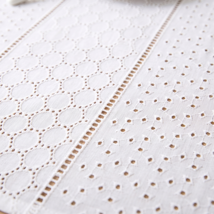 White Cotton Tablecloth – Embroidered in White – Eyelet Circles – close-up of eyelet circles and scattered cutwork on a wooden table