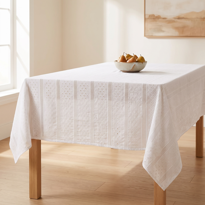 White Cotton Tablecloth – Embroidered in White – Eyelet Bands – covering a wooden table with a bowl of pears beside a window