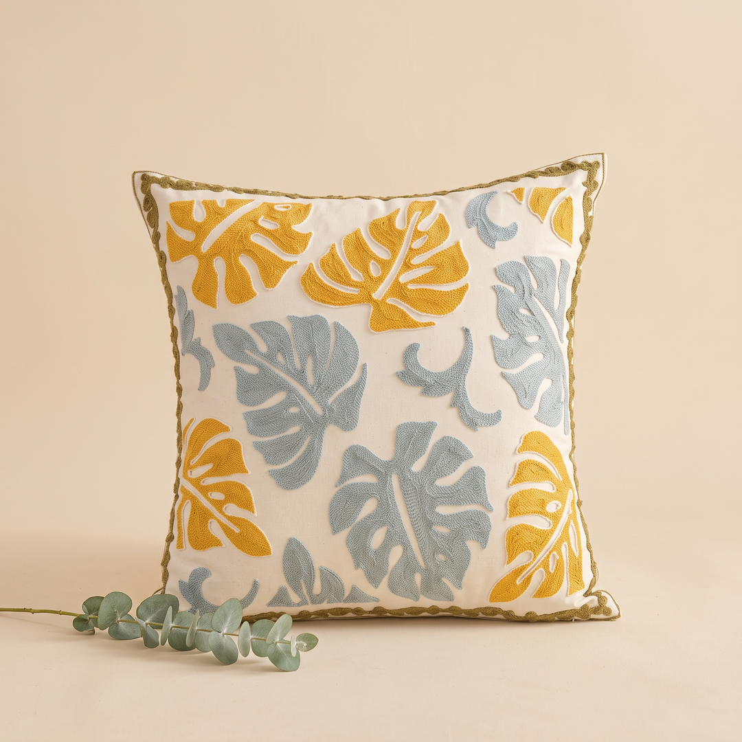 Embroidered Botanical Pillow Cover in Cream – Mustard Monstera – styled with a eucalyptus sprig lying at its base