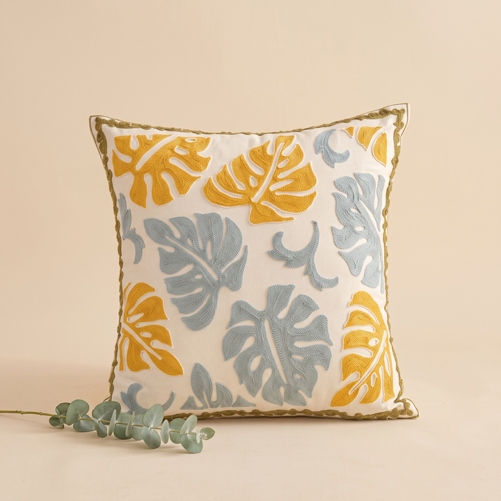 Embroidered Botanical Pillow Cover in Cream – Mustard Monstera – styled with a eucalyptus sprig lying at its base