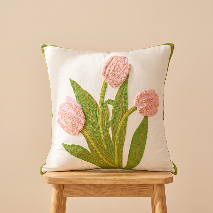 Embroidered Botanical Pillow Cover in Cream – Pink Tulip – centered on a light wood stool against a tan wall