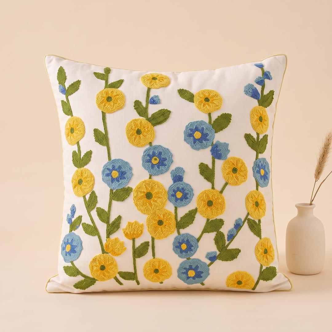 Embroidered Botanical Pillow Cover in Cream – Yellow Wildflower – beside a small ceramic vase holding dried grass stems