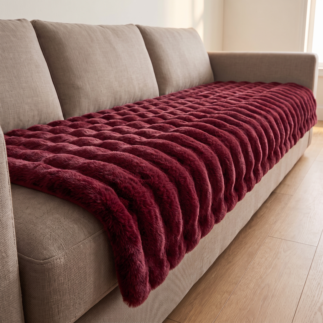 Faux Fur Couch Cover – Plush Bubble Pad in Burgundy – running lengthwise along a sofa seat, seen from the armrest end