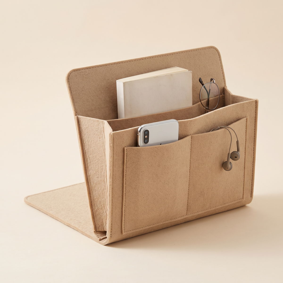 Felt Bedside Caddy – 5 Pockets in Beige – standing open on a plain background holding a book, phone, glasses and earphones