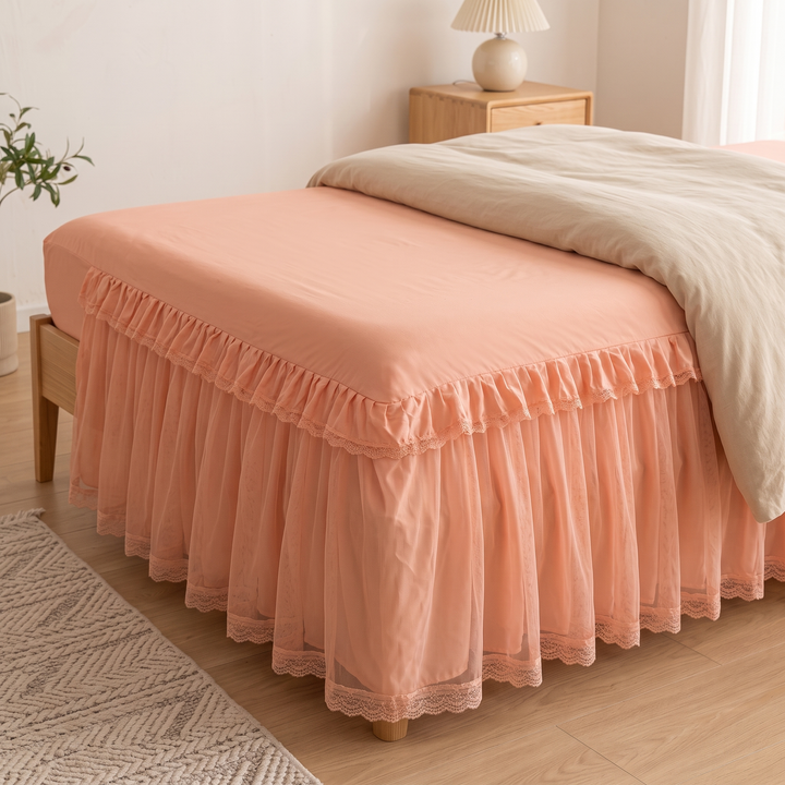 Fitted Ruffled Bed Skirt – Lace Trim in Peach – bed corner with textured rug in foreground and potted plant
