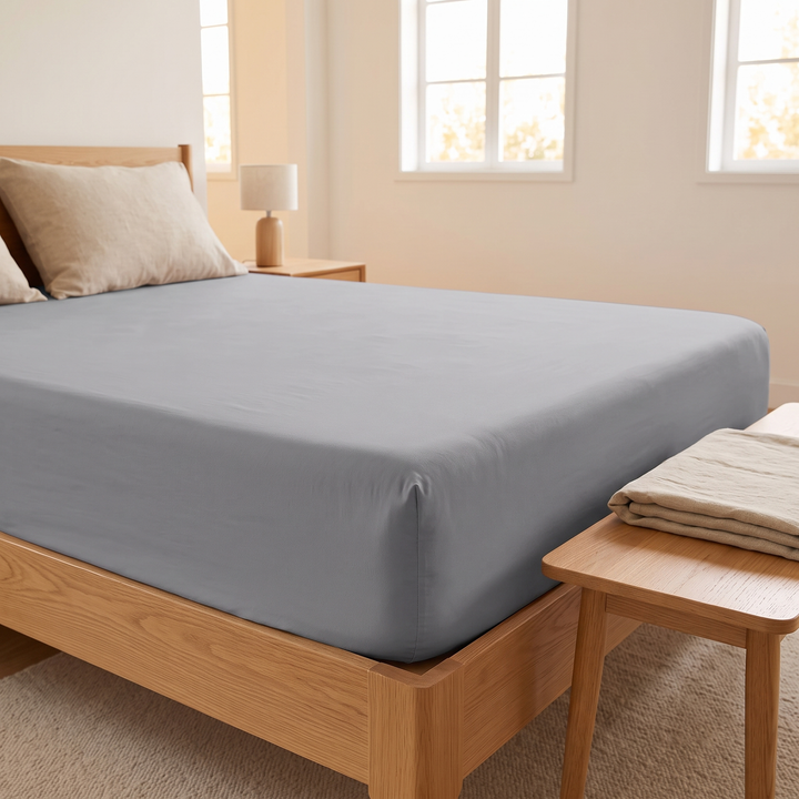 Fitted Sheet in Gray – low corner angle beside a wooden bench with folded bedding