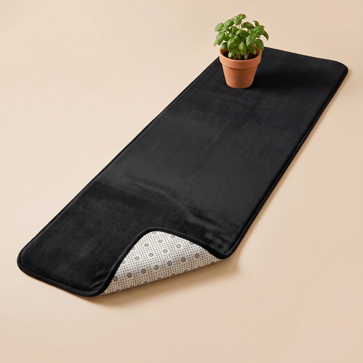 Flannel Kitchen Rug – Cushioned, Non-Slip in Black – angled view with a small potted basil plant at one end