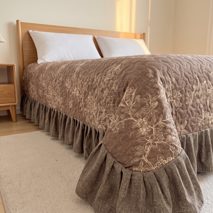 Floral Quilt with Ruffled Edge in Brown Floral – angled view on oak bed beside nightstand and rug