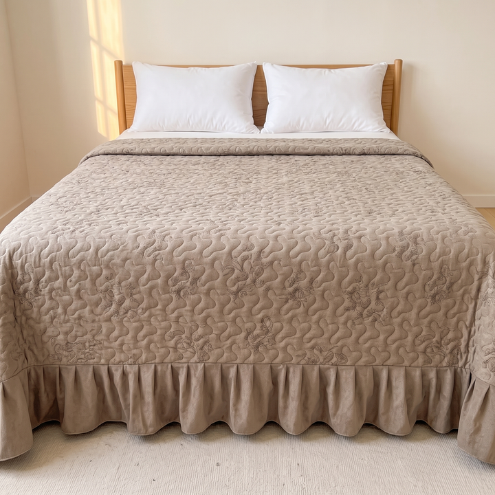 Floral Quilt with Ruffled Edge in Taupe Floral – front view hanging to the floor on an oak-framed bed