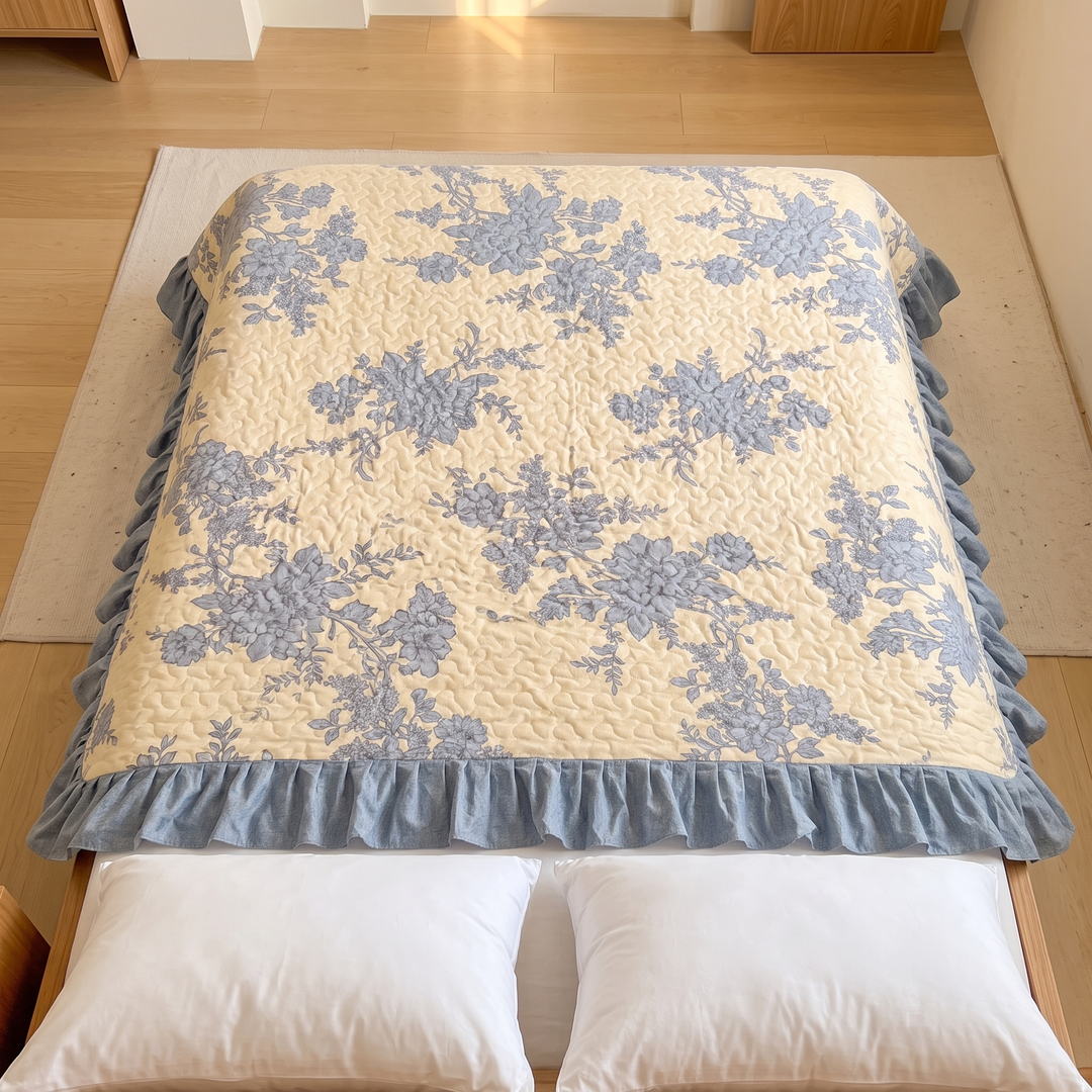 Floral Quilt with Ruffled Edge in Yellow Floral – overhead view spread over a bed on a rug