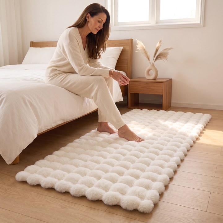 Fluffy Faux Fur Rug – Bubble Texture in White – woman seated on bed edge with bare feet on rug