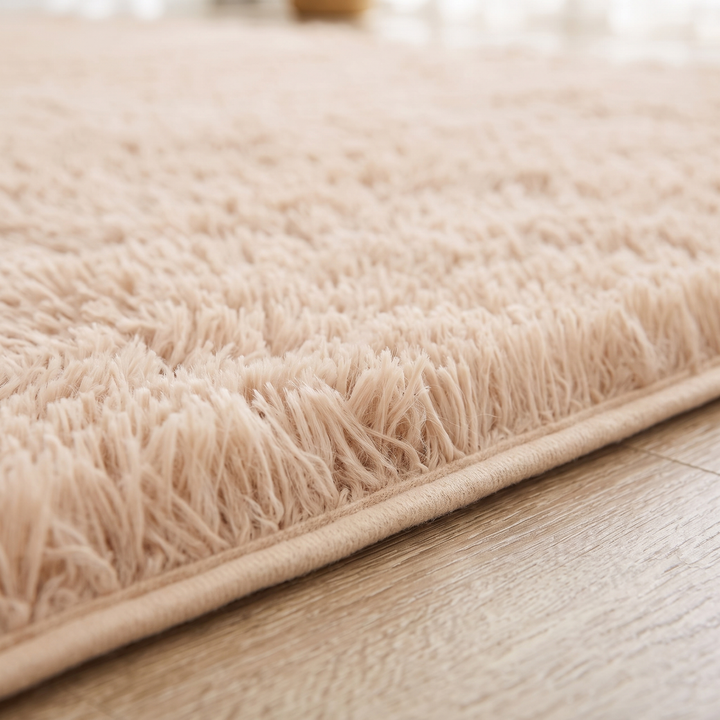 Fluffy Shag Rug in Beige – close-up of the long shaggy pile and fabric edge binding on a wood floor