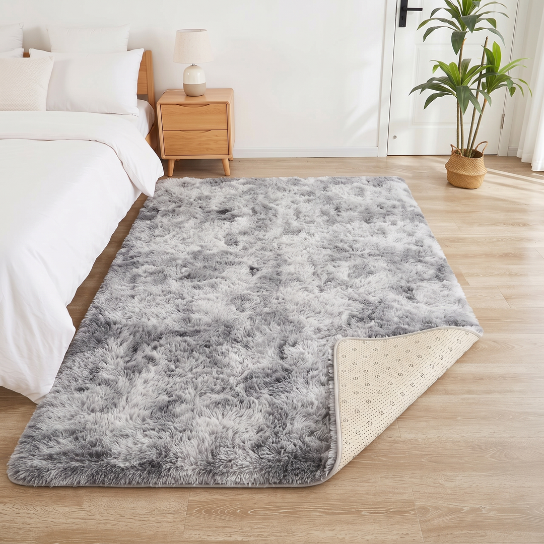 Fluffy Shag Rug in Gray – Tie-Dye – corner turned back, with a table lamp and tall potted plant behind