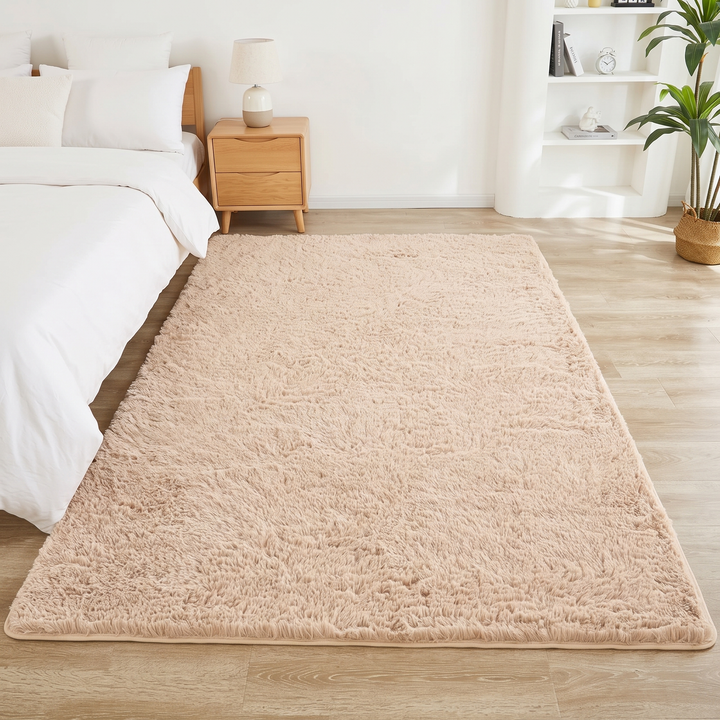 Fluffy Shag Rug in Beige – laid on a wood floor beside a bed in a bright bedroom