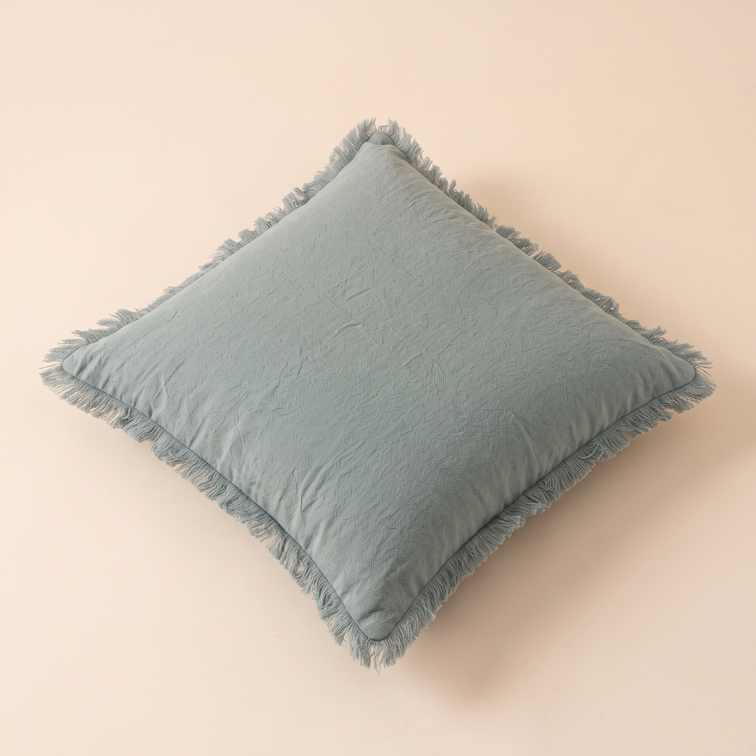 Fringed Pillow Cover in Aqua – lying on its back, turned diagonally, seen from a raised angle