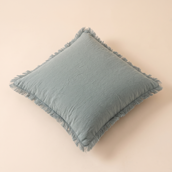 Fringed Pillow Cover in Aqua – lying on its back, turned diagonally, seen from a raised angle