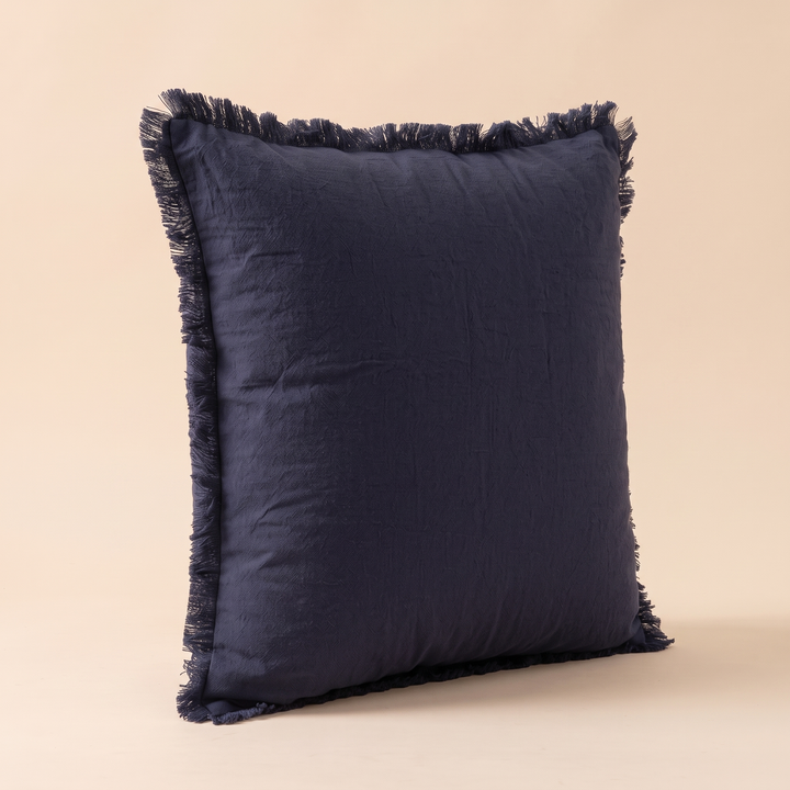 Fringed Pillow Cover in Navy Blue – three-quarter side profile standing alone on a peach surface