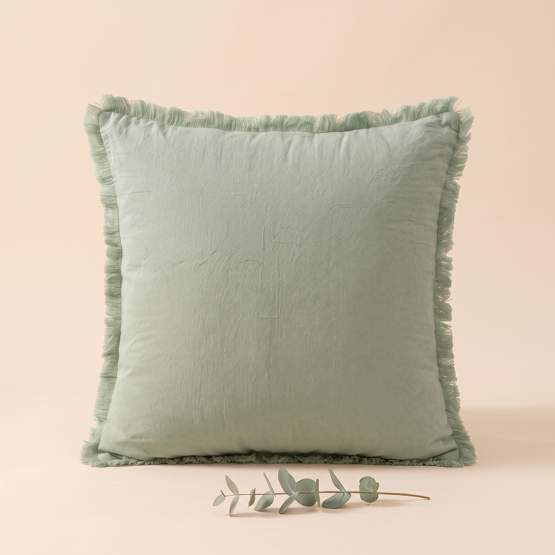 Fringed Pillow Cover in Sage – upright with a small eucalyptus sprig lying in front
