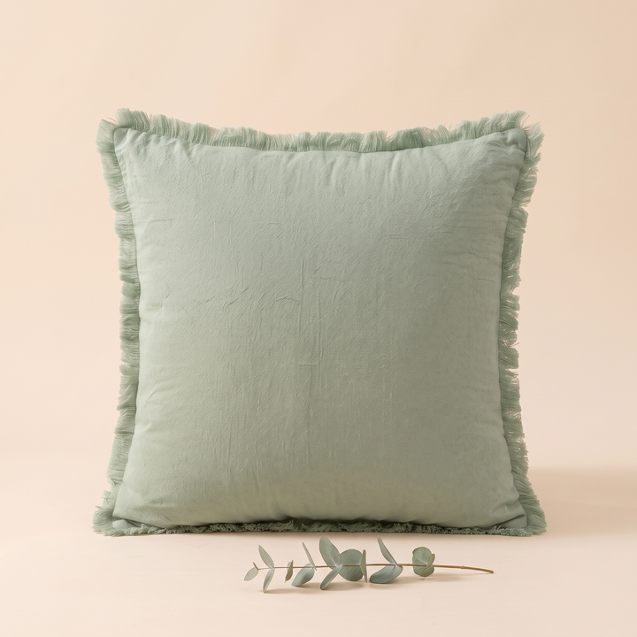 Fringed Pillow Cover in Sage – upright with a small eucalyptus sprig lying in front