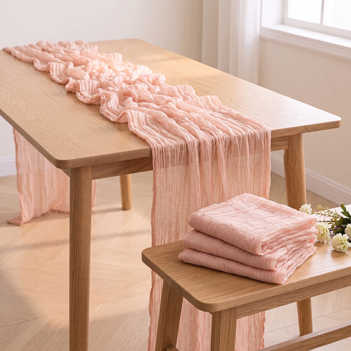 Gauze Table Runners – Set of 4 in Peach – folded stack on bench beside white blossoms, gathered runner behind