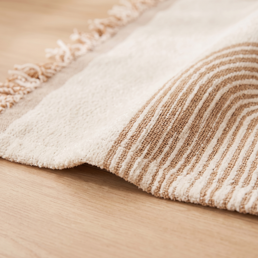 Geometric Chenille Couch Cover with Fringe in Beige – Arch – close-up of the arched stripes and fringe on a wooden surface