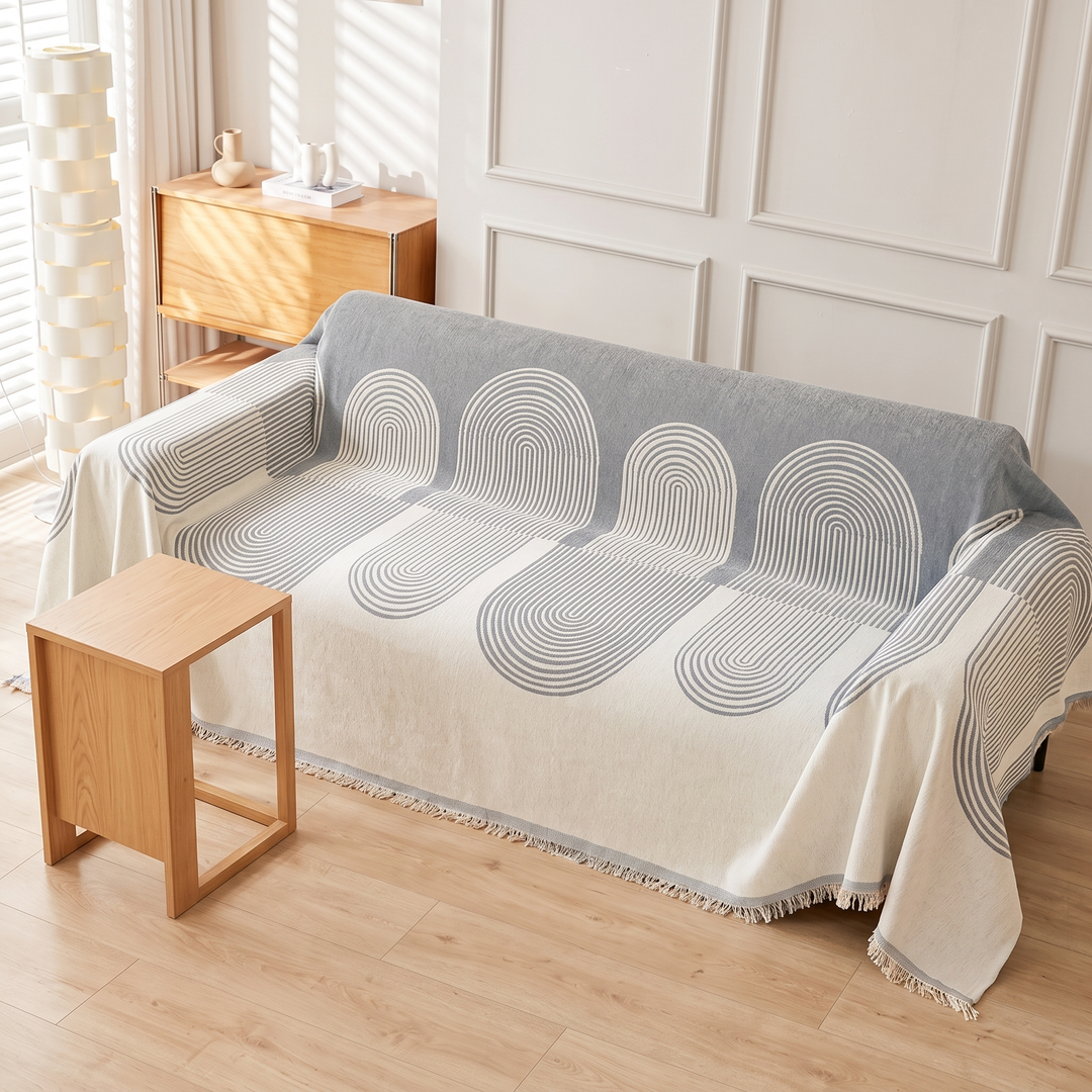 Geometric Chenille Couch Cover with Fringe in Dusty Blue – Arch – seen from above beside a small wooden side table
