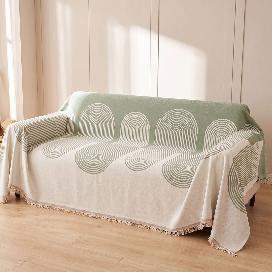 Geometric Chenille Couch Cover with Fringe in Sage – Arch – spread over a sofa in soft sunlight on wood flooring
