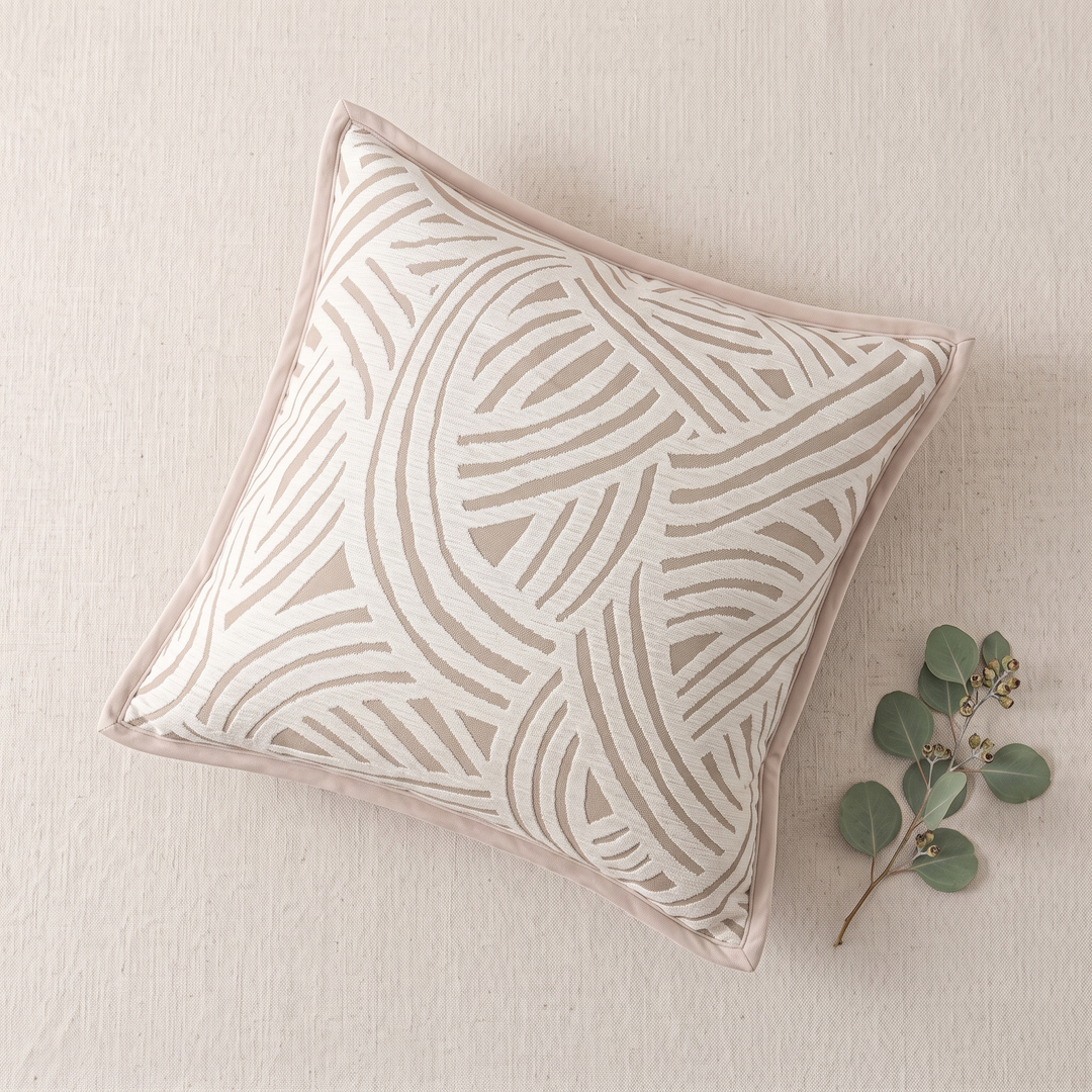 Geometric Throw Pillow Cover – Jacquard in Beige – Swirl – overhead flat lay on a textured cream surface with eucalyptus sprig