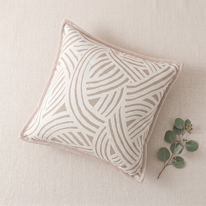 Geometric Throw Pillow Cover – Jacquard in Beige – Swirl – overhead flat lay on a textured cream surface with eucalyptus sprig