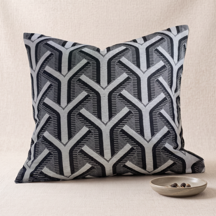 Geometric Throw Pillow Cover – Jacquard in Black – Arrow – beside a small stone dish holding dried seeds